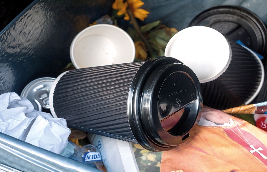 black coffee cup inside bin outside in public